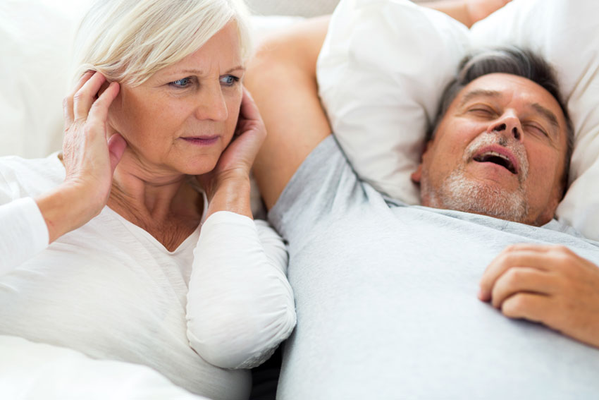 adult man snoring while wife plugs her ears