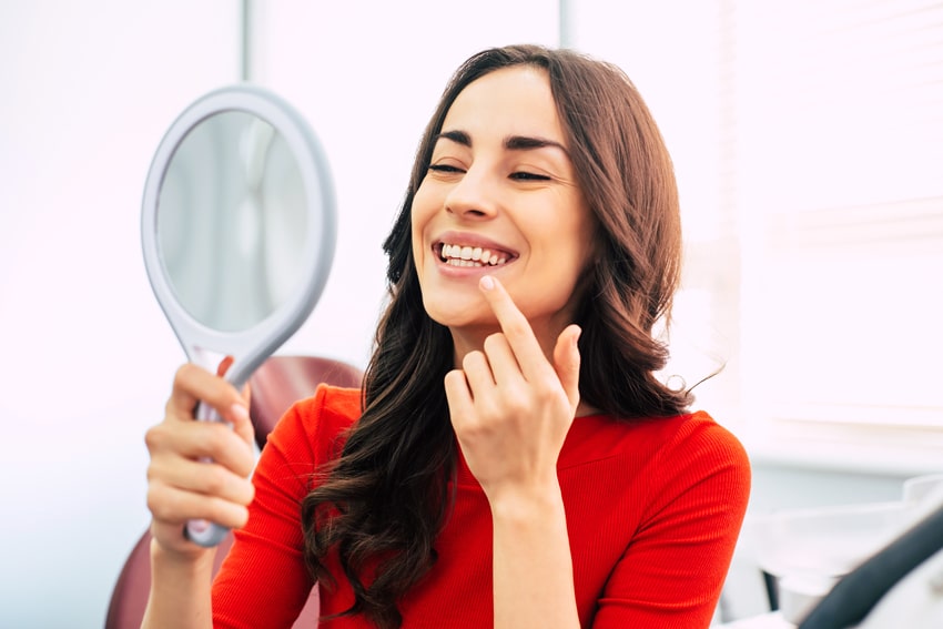 adult woman looking at her teeth in a mirror