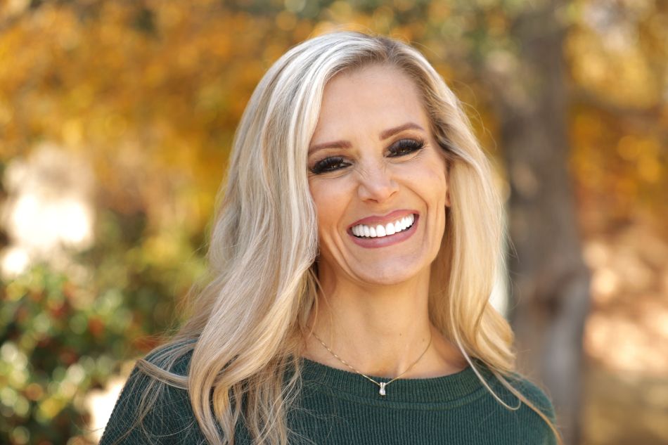 A beautiful woman with blonde hair standing outside smiling